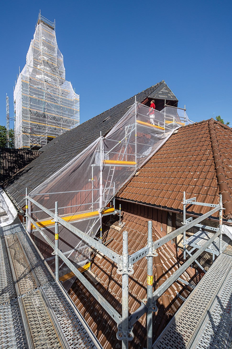 Kirchenschiff und Kirchenturm umschmiegt ein PERI UP Arbeits- und Schutzgerüst – mit großzügigen und stolperfrei ausgeführten Arbeitsebenen zur unproblematischen und fachgerechten Durchführung