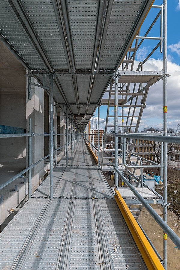 Markantes Konstruktionsdetail beim PERI UP Easy Fassadengerüst ist der integrierte Gerüstknoten. Riegel, Auflagen und Konsolen werden direkt in die Öffnung des Rosett-Knotens eingehängt; es sind keine Kupplungen notwendig. So lassen sich auch Ecken oder außenliegende Treppenläufe schnell montieren.