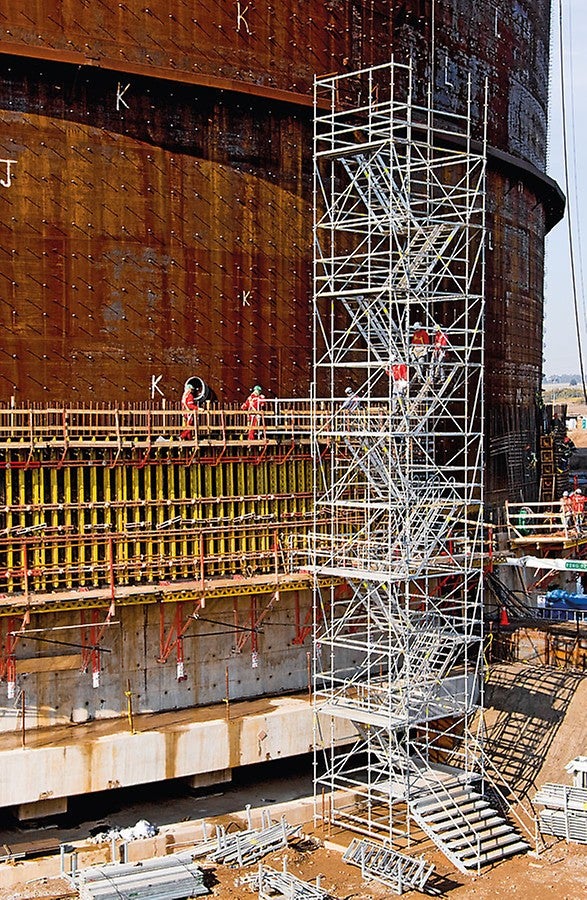 Stair tower with twin staircase units for the construction of a liquid gas tank. Guardrails mounted on the outer and middle stringers provide safe passage.