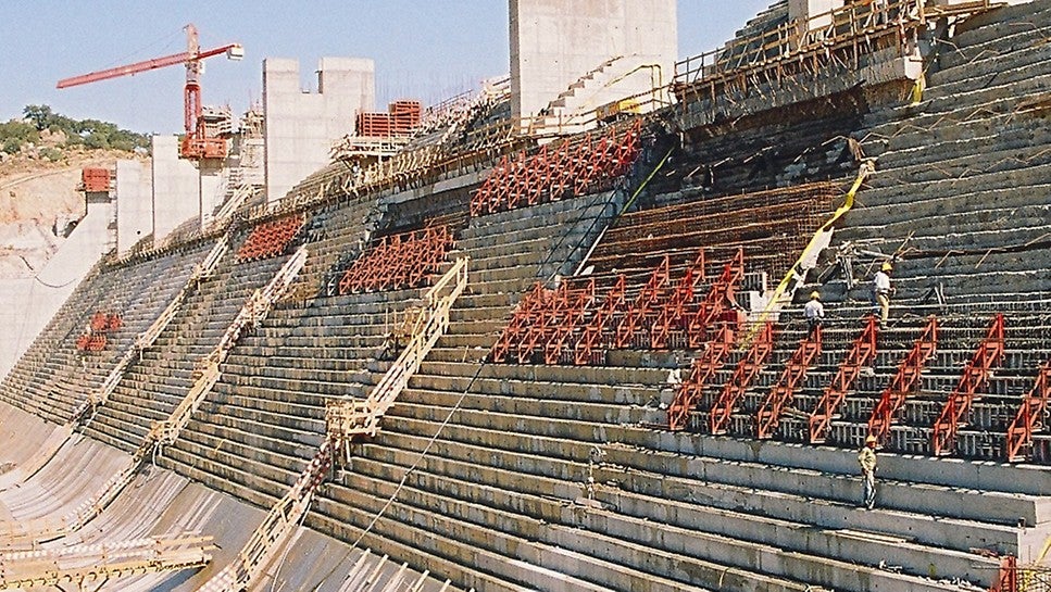 Vista geral do paramento jusante em fase de recobrimento de betão convencional.<br/>