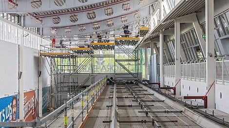 Auf dem Schutztunnel montierte Alu-Fahrschienen des LGS Systems ermöglichen die Verfahrbarkeit der abgetreppten Arbeitsbühne zur Dachbinderbearbeitung.