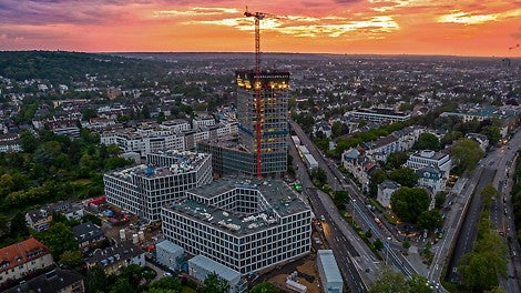 Parallel zur Fertigstellung der Sockelgeschosse ließen sich am 100-m-Hochhaus innerhalb der sukzessive mitgeführten PERI RCS Einhausung alle Schalungs-, Bewehrungs- und Betonierarbeiten unterbrechungsfrei ausführen.<br/>(Foto: Art-Invest / KIRO, Markus Kirch