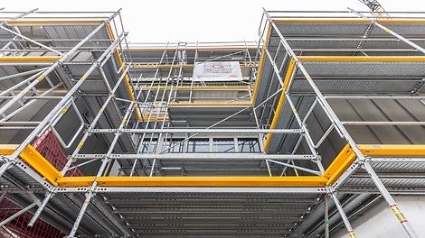 Der Gerüstknoten am Easy-Stiel ermöglichte außen- und innenseitige Anbauten und den nahtlosen Übergang von Easy- auf Flex-Bauteile, beispielsweise für die Schutzdachausbildung im Zugangsbereich zur Halle und als vorgelagerte Absetzbühne.