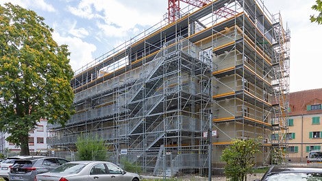 Ein 10 m hoher Treppenturm mit 35 m langen Laubengängen auf Basis der PERI UP Public Gerüstlösung macht gartenseitig alle vier Wohnebenen für die Bewohner während der Baumaßnahme zugänglich.