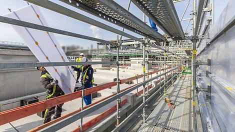 Die blickdichten, aber dennoch lichtdurchlässigen Paneele des PERI UP Cladding sind leicht und lassen sich aus gesicherter Position einfach und effizient montieren