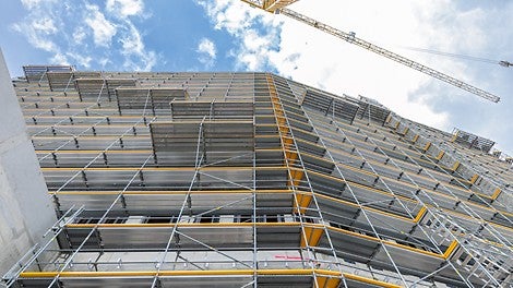 In das PERI UP Fassadengerüst integrierte Absetzbühnen kragen jeweils 1,50 m nach außen aus und dienen zur Andienung, Lagerung und Vormontage der Fassadenelemente.