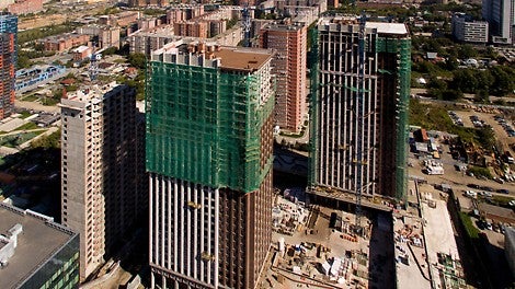 Прямоугольник фасада разбит на две вертикальные полосы: узкая краснокирпичная отступает от широкой светлой плоскости и завершается на высоте 100 м. широко выступающим карнизом