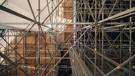 Фасадные декоративные панели в форме перьев монтировались к стойкам и ригелям лесов с помощью металлических пластин и хомутов. А наличие розеток у стоек, отверстий в ригелях и прочих конструктивных особенностей системы PERI UP Flex значительно упростило этот процесс.