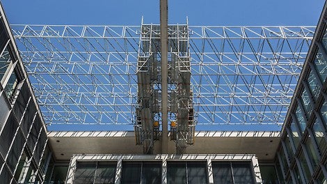 Das Verfahren der Hängegerüsteinheiten erfolgt ohne Mobilkranunterstützung auf Fahrwerken entlang der Gebäuderänder. Nach dem Schließen der Zwischenfelder in Längs- und Querrichtung – inklusive der unteren Belagebene – ist der Betonträger vollständig umschlossen.