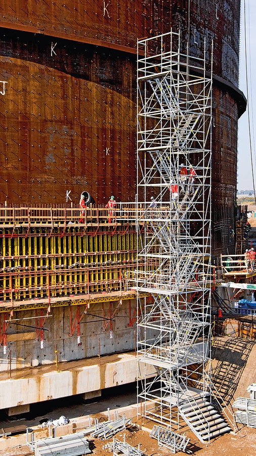 图示为一个液化天然气罐工程中使用的双跑施工梯塔架，外部的防护栏以及中间的楼梯斜梁提供了安全的通道。