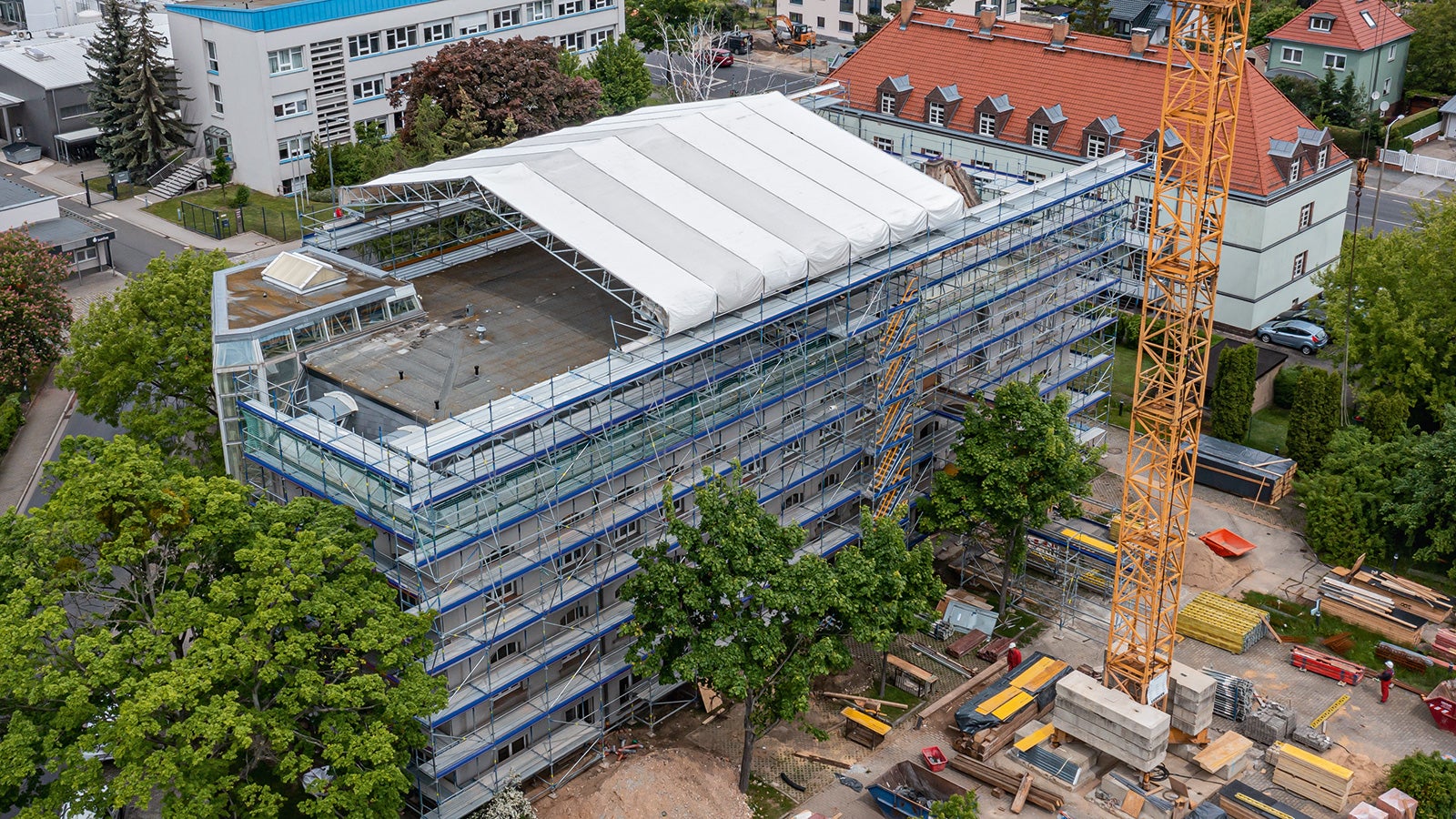 Zur Durchführung der aufwendigen Baumaßnahme muss die Gebäudesubstanz des Bestandsbauwerks während der gesamten Umbauphase gegen äußere Witterungseinflüsse geschützt werden.