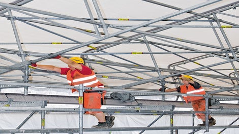 顶棚单元可在桁架长度方向上推动，例如可通过吊车吊起内部施工的材料。