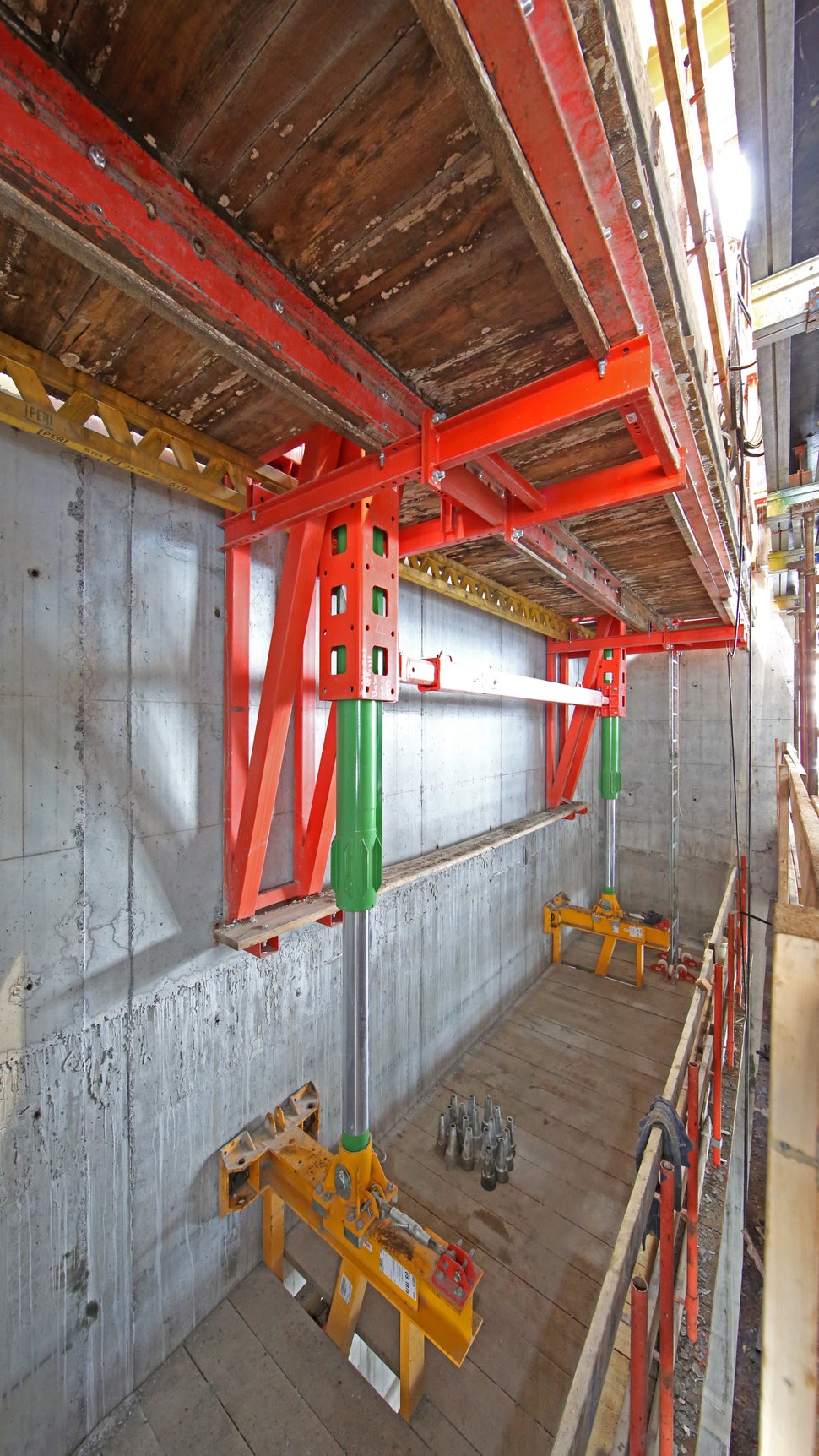 The green hydraulic cylinder pushes off of the yellow climbing bracket to advance the red working bracket – which carries the entire system, consisting of formwork and platforms – to the next level. The climbing bracket will later re-use the same anchor points as the working bracket, resulting in significant time savings.