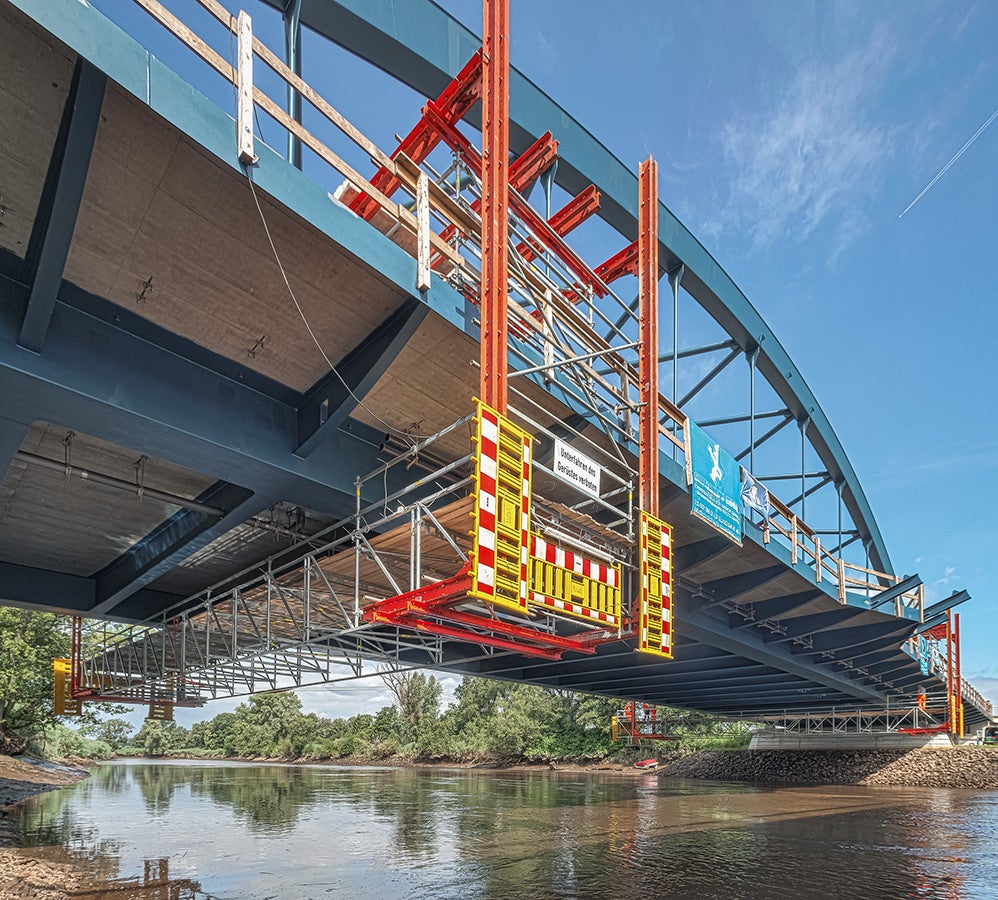 Die 110 m lange Bogenbrücke überquert die Wümme und verbindet gleichzeitig Bremen mit Niedersachsen. Zwei fahrbare PERI Gerüstplattformen auf Basis des LGS Fachwerkbindersystems machten die Arbeiten unter der Brücke unabhängig von äußeren Randbedingungen.