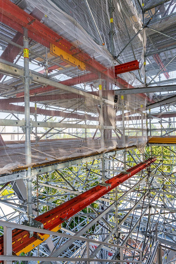 Wo Vertikalstiele aufgrund der Funkturmgeometrie nicht von unten bis oben durchgeführt werden konnten, dienten Stahlträger des VARIOKIT Ingenieurbaukastens zur Aufnahme und horizontalen Lastverteilung der weiterführenden, entsprechend versetzt angeordneten Gerüststiele.
