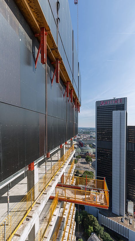 L'enceinte avec le mur de protection pour l'escalade RCS entourait les étages supérieurs du gros œuvre et protégeait le personnel contre les chutes et les vents forts à grande hauteur. Les plateformes d'extension RCS et les protections latérales PROKIT complétaient judicieusement la solution globale PERI.