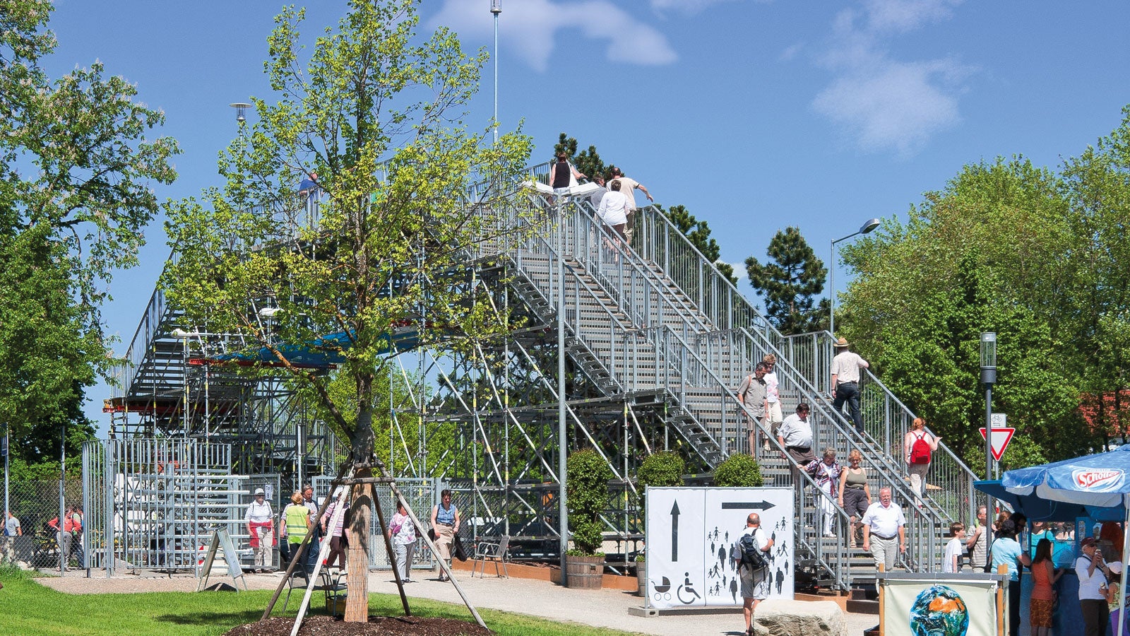 Solución para una feria: escalera que conduce a un puente peatonal que cruza una carretera de varios carriles.