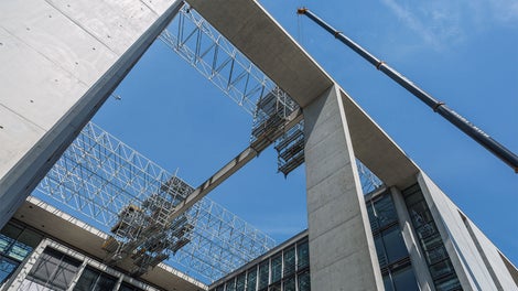 Per i lavori di risanamento delle travi in calcestruzzo esposte, un'impalcatura sospesa mobile PERI UP si estende sul paesaggio dei tetti del Bundestag di Berlino.